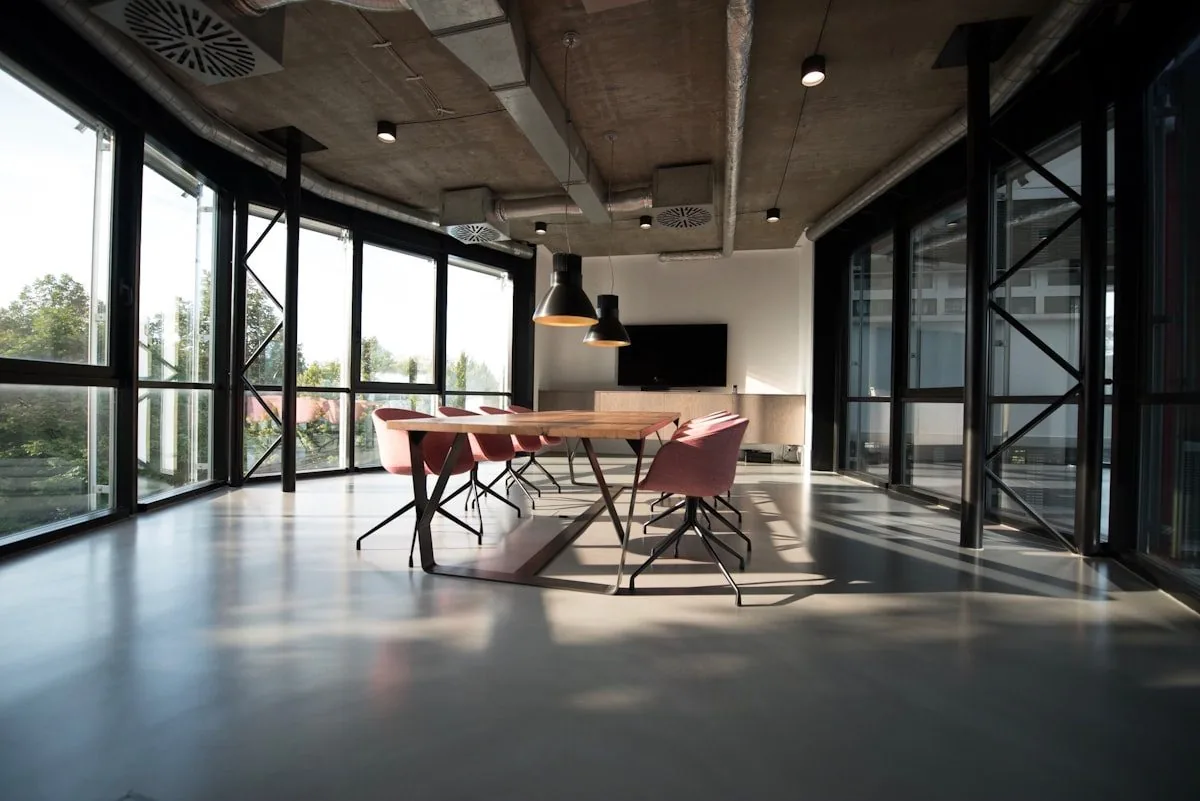 An empty modern meeting room with a long wooden table, chairs and a wall-mounted screen