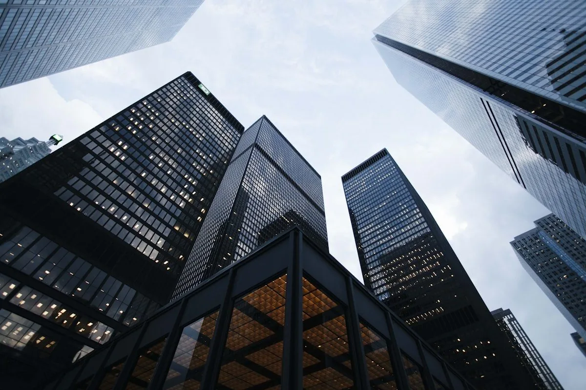 A view looking up at glass office towers against a pale sky