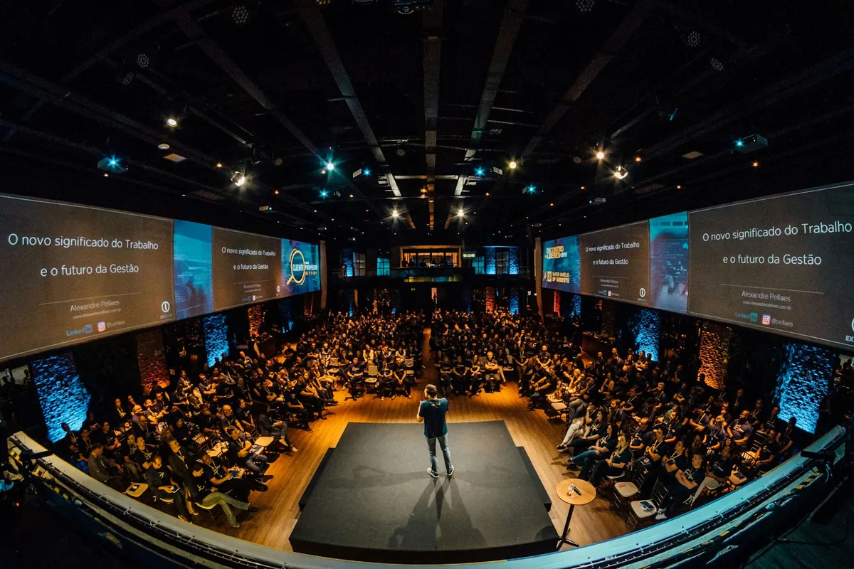 A speaker addressing a large audience from a stage